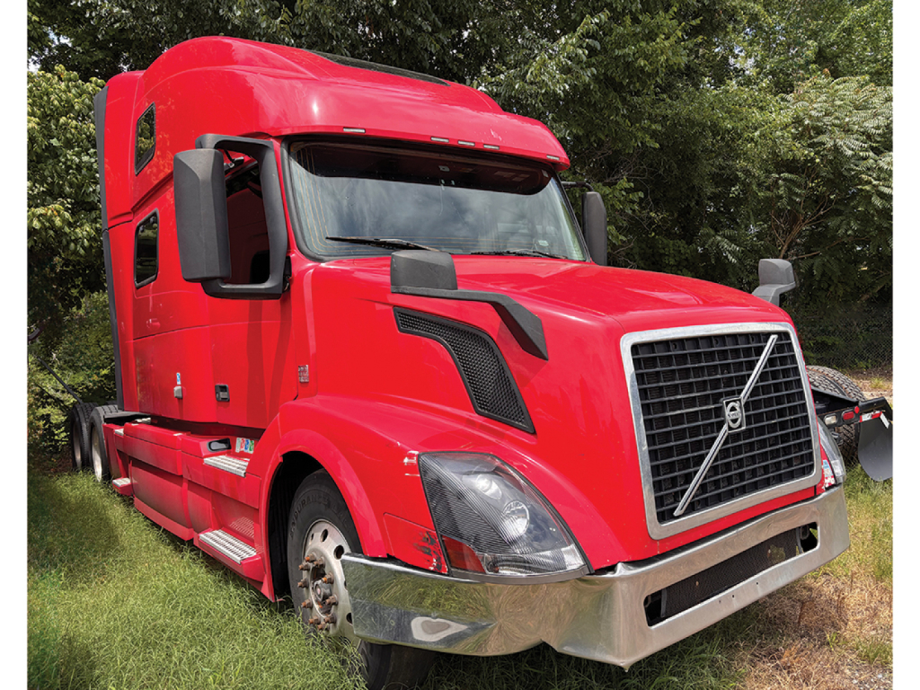 Volvo VNL 780 sleeper cab tractor in red with large grille and black side mirrors, front bumper and chrome lower fascia visible.