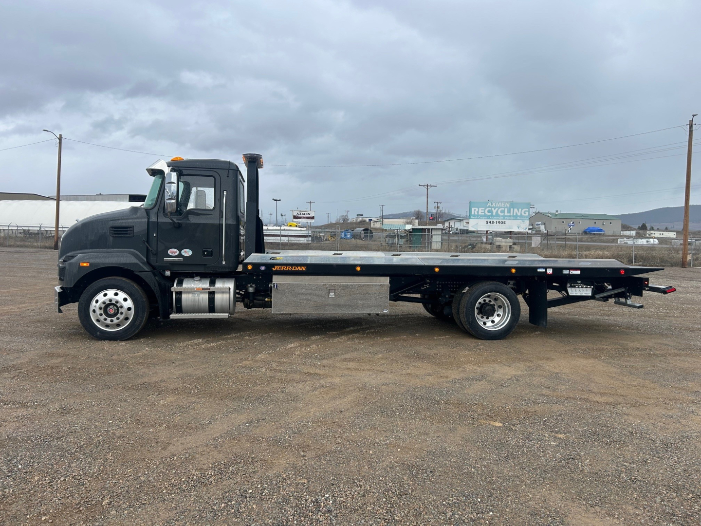 Truck side view showing a black 2026 Mack MD6 rollback wrecker with long flatbed and dual rear wheels, VIN 1M2MDBAAXTS018745 visible in listing, stock 68694.