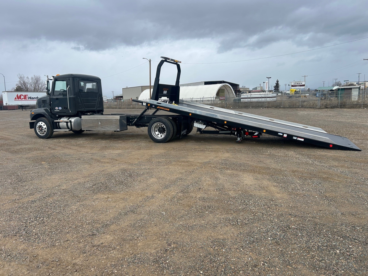 Tractor unit with flatbed tow truck in-service showing long black rollover ramp and cab, no visible branding details.