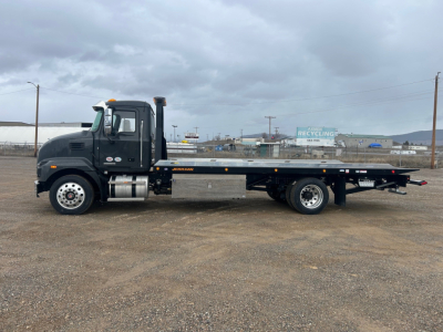 Truck side view showing a black 2026 Mack MD6 rollback wrecker with long flatbed and dual rear wheels, VIN 1M2MDBAAXTS018745 visible in listing, stock 68694.