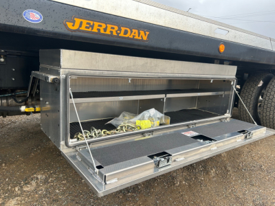Truck bed toolbox on a 2026 Mack MD6 rollback with open storage compartment showing metal toolbox and securing chains.