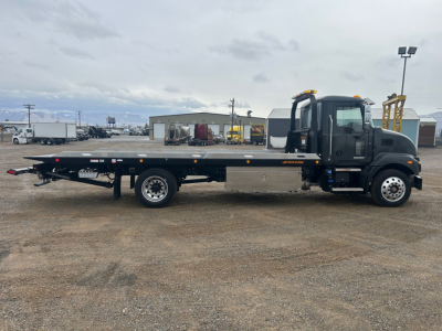 Mack MD6 rollback truck side view showing flatbed car hauler and cab with orange clearance lights.