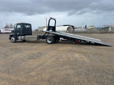 Tractor unit with flatbed tow truck in-service showing long black rollover ramp and cab, no visible branding details.