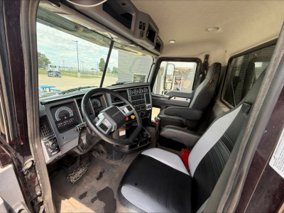 Cab interior of a 2025 Mack PI64T truck showing steering wheel with Mack logo, dashboard gauges, and front passenger seat.