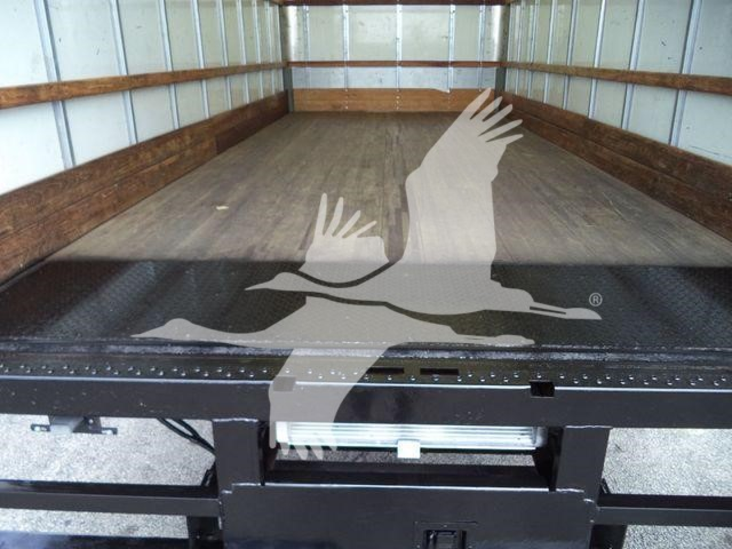 Truck bed of a 2011 Ford E450 box truck showing empty cargo area and ramp gate.