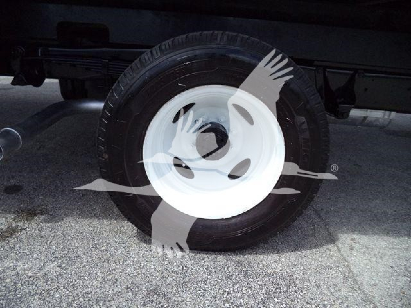 Truck wheel and tire with white steel rim under Ford E-450 box truck. Visible in-service wheel assembly with tire; no legible labels or text.