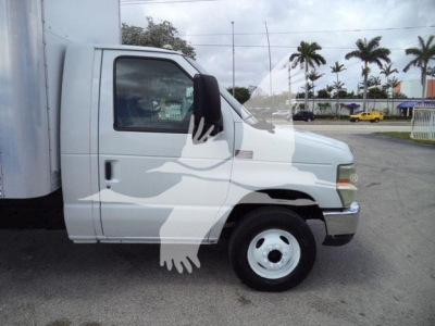 Ford E-450 box truck side view showing front cab and wheel with stickered door window reflecting palm trees.