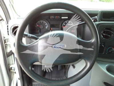 Ford E-450 dashboard and steering wheel seen through front cabin with gauges and center console.
