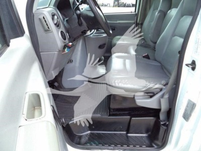 Ford E-450 cargo van interior showing driver and front passenger seats with steering wheel and entry step area visible.