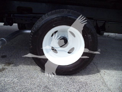 Truck wheel and tire with white steel rim under Ford E-450 box truck. Visible in-service wheel assembly with tire; no legible labels or text.