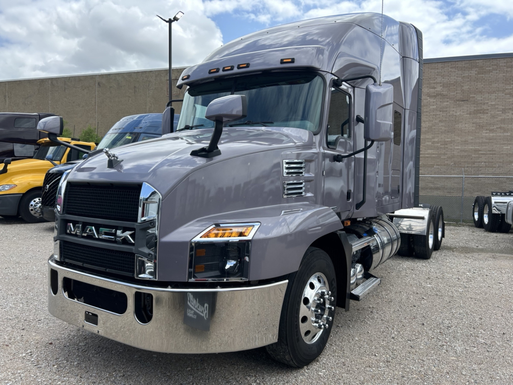Mack AN64T70 conventional sleeper truck in gray, front-left view with chrome bumper and grille; visible text includes MACK on grille and side mirrors; no other legible labels.