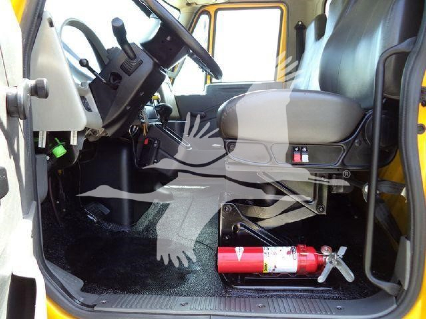 Cab interior of a 2019 International 4300 truck showing steering column, dashboard, and a red fire extinguisher mounted under the seat.