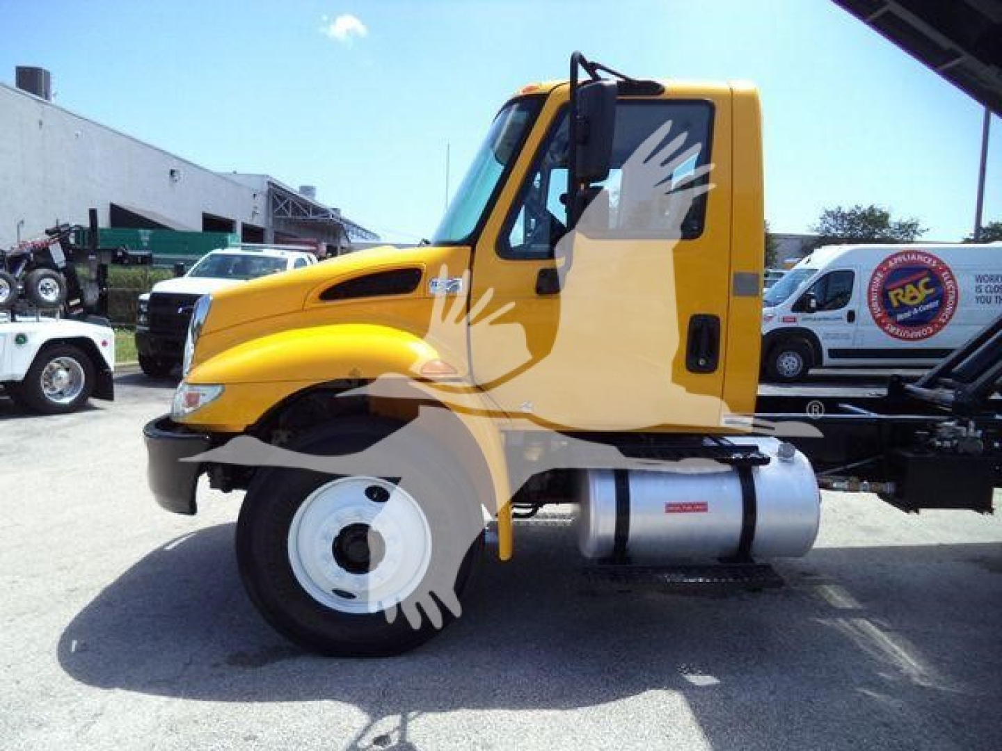 2019 International 4300 cab and chassis side view showing yellow cab and large fuel tank on a truck dealership lot.