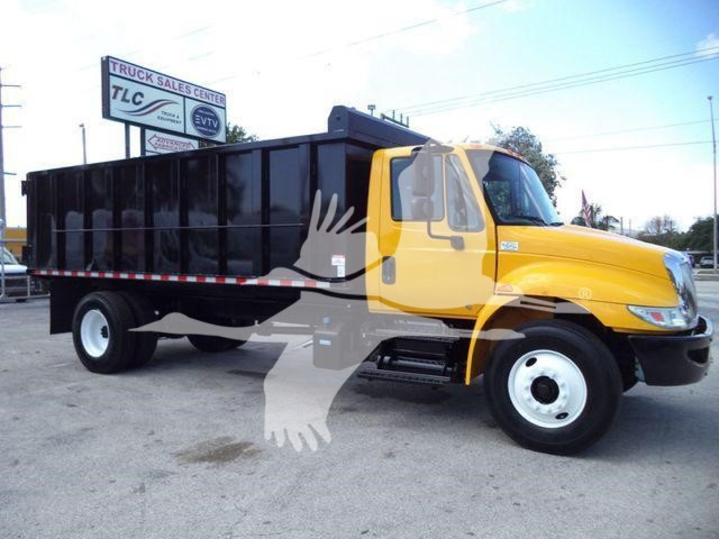 Truck image showing a yellow and black International 4300 dump truck in a lot with a large black dump bed.