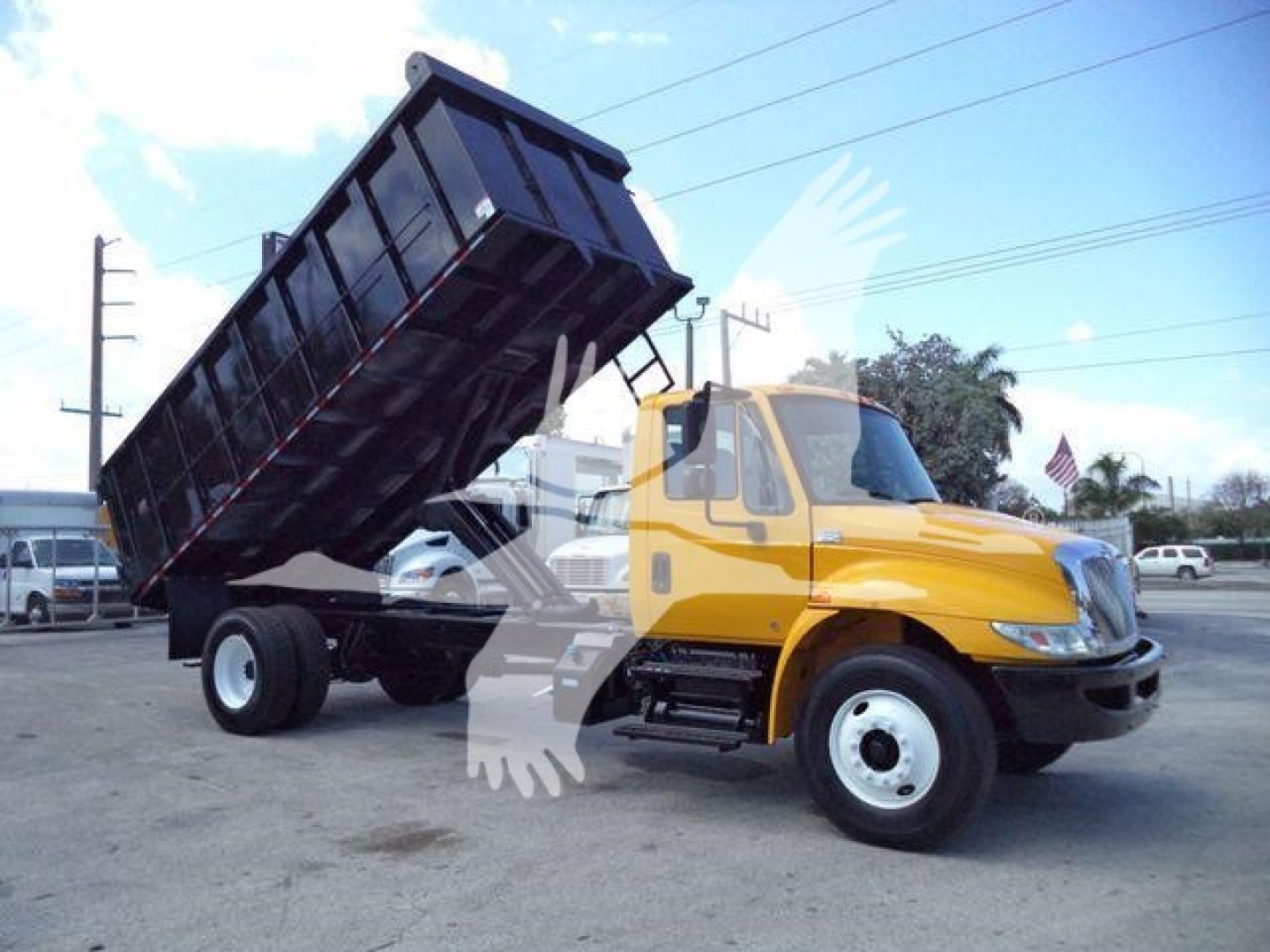 2019 International 4300 dump truck with yellow cab and raised black dump body, front view at an outdoor lot.