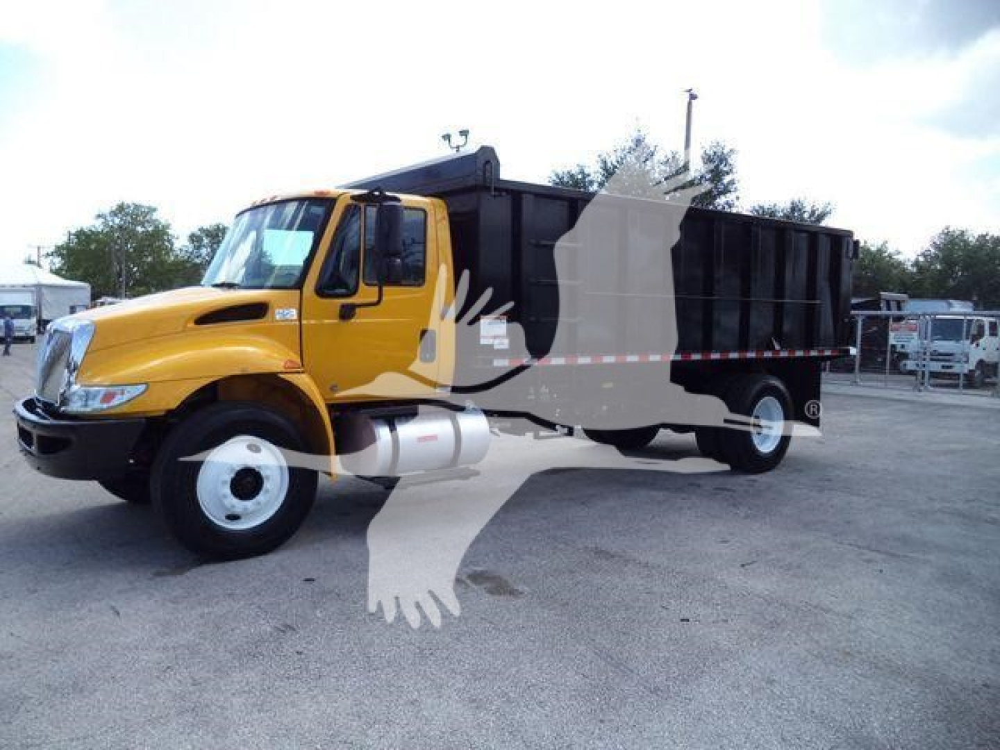 Truck image showing a yellow International 4300 dump truck with a black dump body, side view in a parking lot.