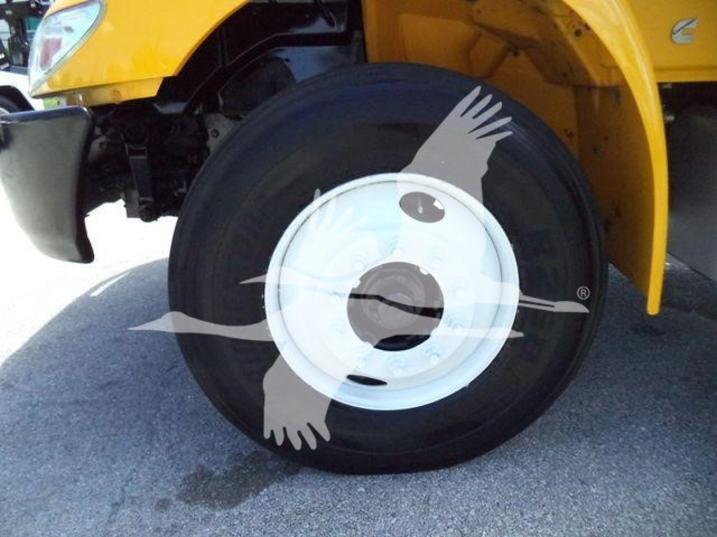 Wheel of a yellow International truck showing a close-up of a black tire with white steel wheel and partial fender.