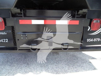 Back of a 2019 International 4300 truck showing a metal rear bumper with two ring handles and red/white reflective tape. Partial text on left: '... EQUIPMENT' and a phone number; right side shows '954-...'.