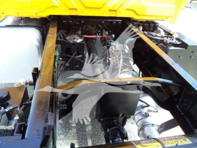 Truck engine bay view showing V-shaped metal frame and engine components under the hood of a 2019 International 4300 used landscape truck.