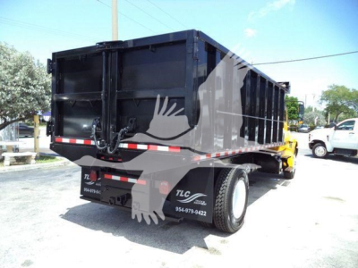 Dump truck bed shown from rear-left side with black dump body and dual rear wheels.