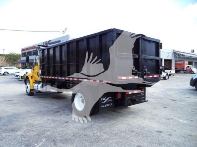 Truck bed of a 2019 International 4300 dump truck with black bed and yellow cab; visible text on side includes logo and contact numbers, rear lights, and reflective tape.