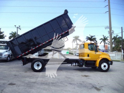 Truck: 2019 International 4300 dump bed tilted for loading, yellow cab, black dump bed, side view showing chassis and dual rear wheels.