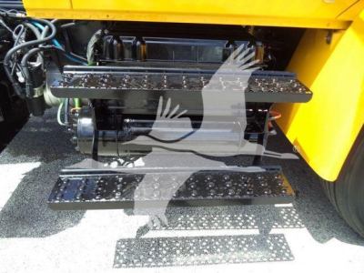 Truck steps and engine bay of a 2019 International 4300 with black metal fold-out steps and visible engine components.