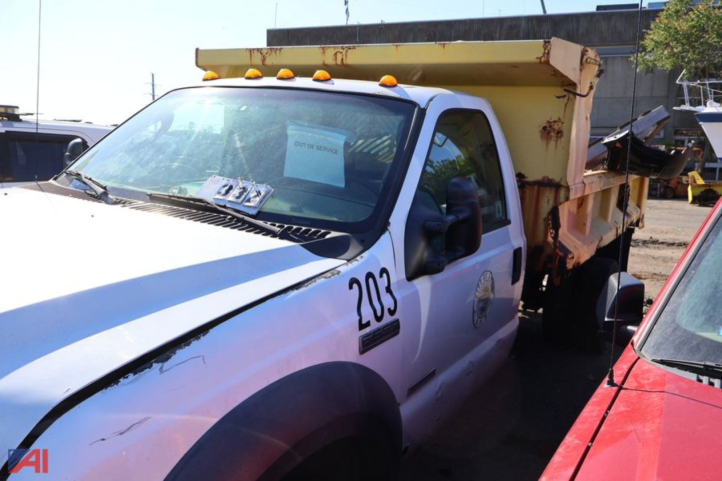 Ford F-550 Super Duty dump truck cab with yellow dump bed, number 203 on door, in-service condition visible in a yard.