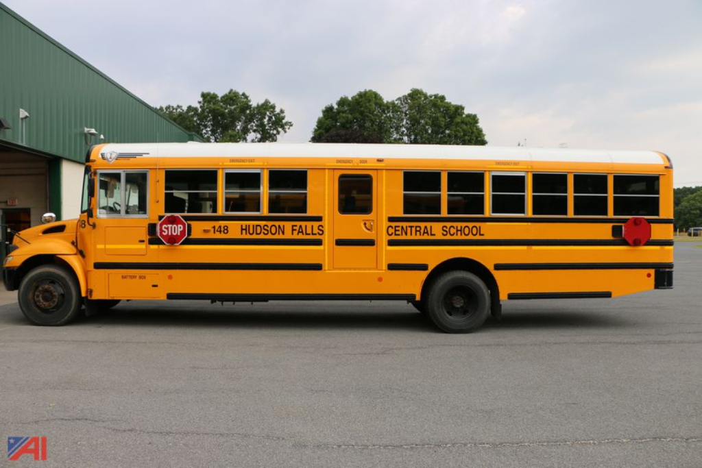 Yellow IC Corporation CE Series school bus with kids stop sign and Central School Hudson Falls, side view.