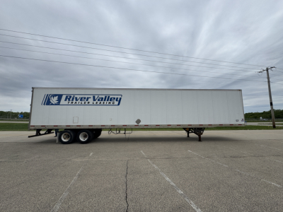 Trailer side view showing River Valley Trailers Leasing logo on a white utility trailer with dual rear axles and a ramp door.