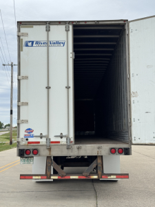 Trailer rear view showing open cargo area of a white River Valley trailer with back doors, taillights, and bumper.