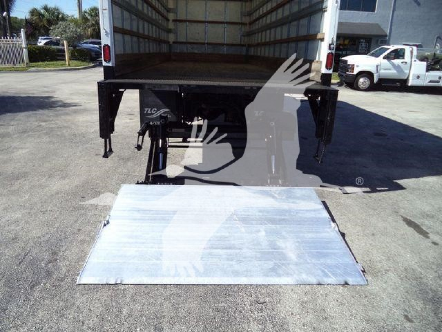 Truck bed with loading ramp lowered showing back of 2019 International 4300 box truck and stock area in background.