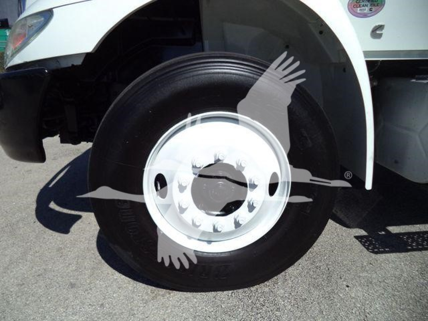 Front wheel well and hub of a 2019 International 4300 box truck showing front tire and white rim.