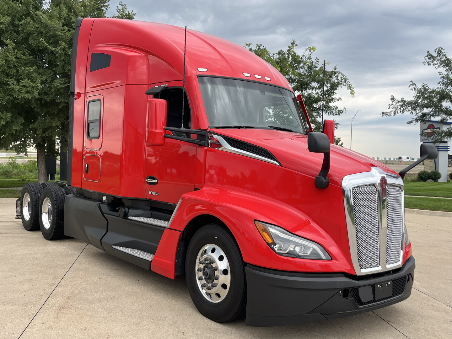 Kenworth T680 semi truck in red color shown from front-left side with sleeper cab.