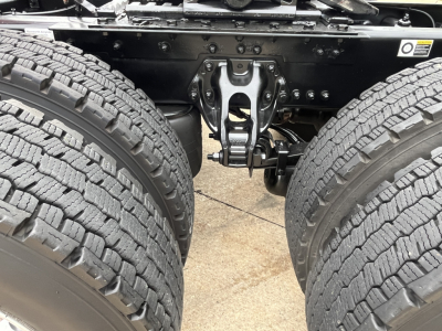 Kenworth T680 chassis view showing dual rear axles and suspension hanger; visible are tires, frame rails, and brake components.