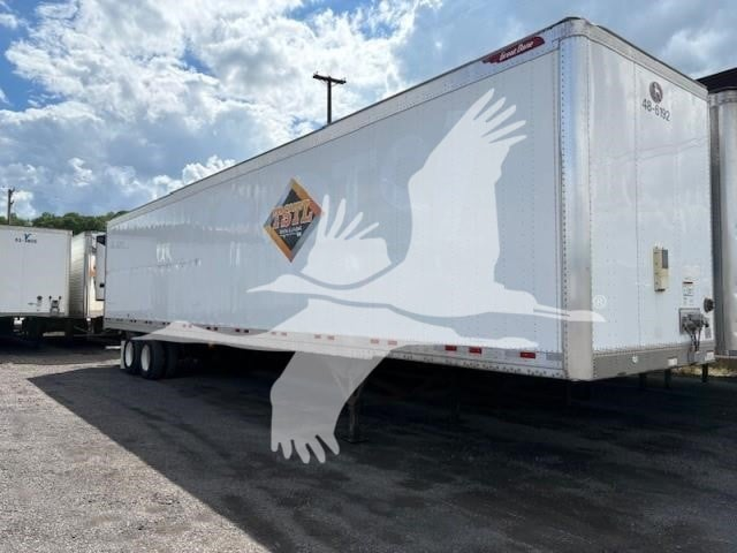 Great Dane dry van trailer in a parking lot showing a white silhouette crane and a logo on the side.