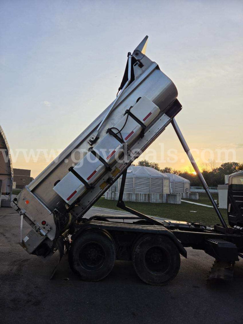 Truck bed with a raised dump body on a tractor with dual rear wheels; side view shows hydraulic cylinders and metal panels. watermark across middle.