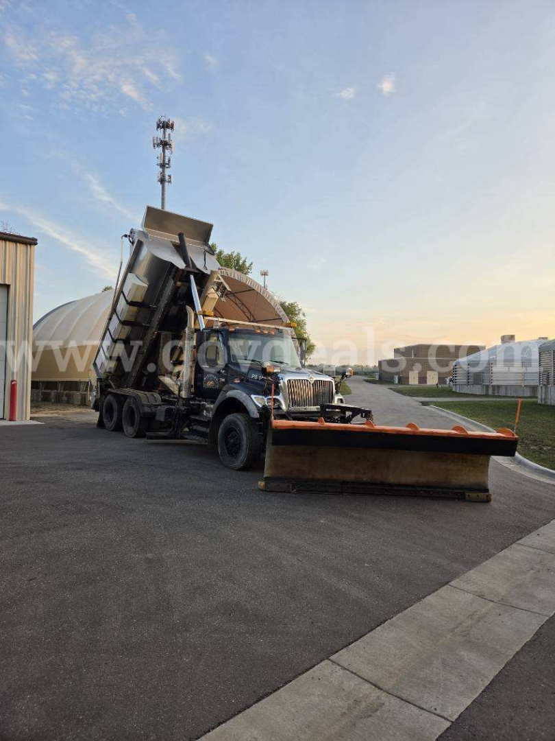 International WorkStar 7600 truck with plow attachment in a lot, side view showing cab, dump bed, and front plow blade.