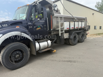 International WorkStar 7600 dump truck in side view showing cab and dump bed, black front fender, logo and 7600 badge on door, stock wheels, industrial surroundings.