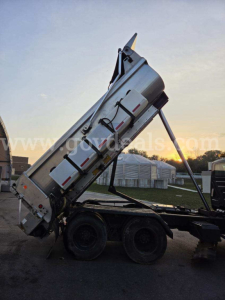 Truck bed with a raised dump body on a tractor with dual rear wheels; side view shows hydraulic cylinders and metal panels. watermark across middle.