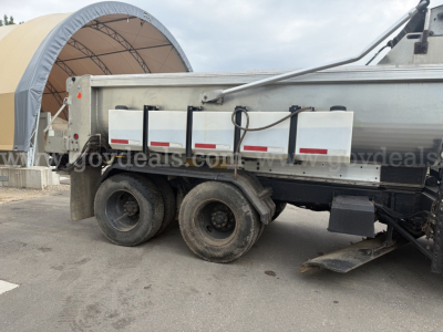 Truck bed side with dual rear axles, International WorkStar 7600 plow truck, visible fuel tanks and mounting hardware.