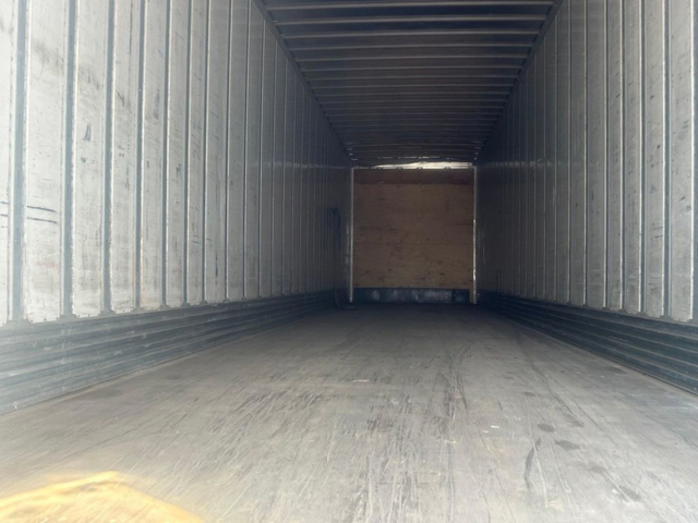 Trailer interior view of a long empty cargo bay with wooden bulkhead at far end.