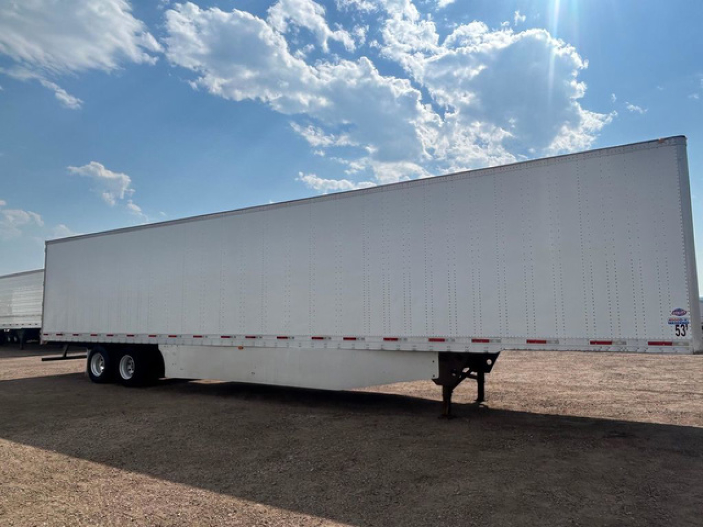 Trailer (box) side view showing utility van trailer with no visible branding and wheel axles in the distance.