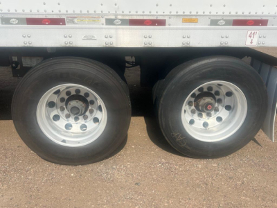 Dual rear trailer wheels showing steel rims and tires under a utility trailer chassis.