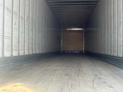 Trailer interior view of a long empty cargo bay with wooden bulkhead at far end.