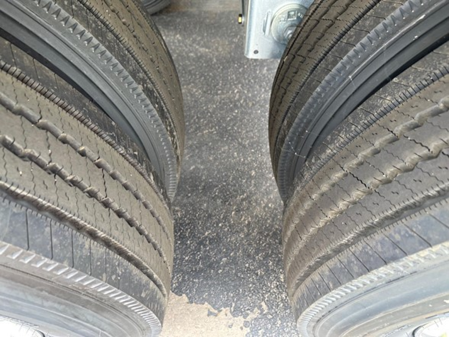 Twin rear tires of a Mac Macsimiser 1/2 round aluminum end dump trailer showing dual tires and trailer frame.