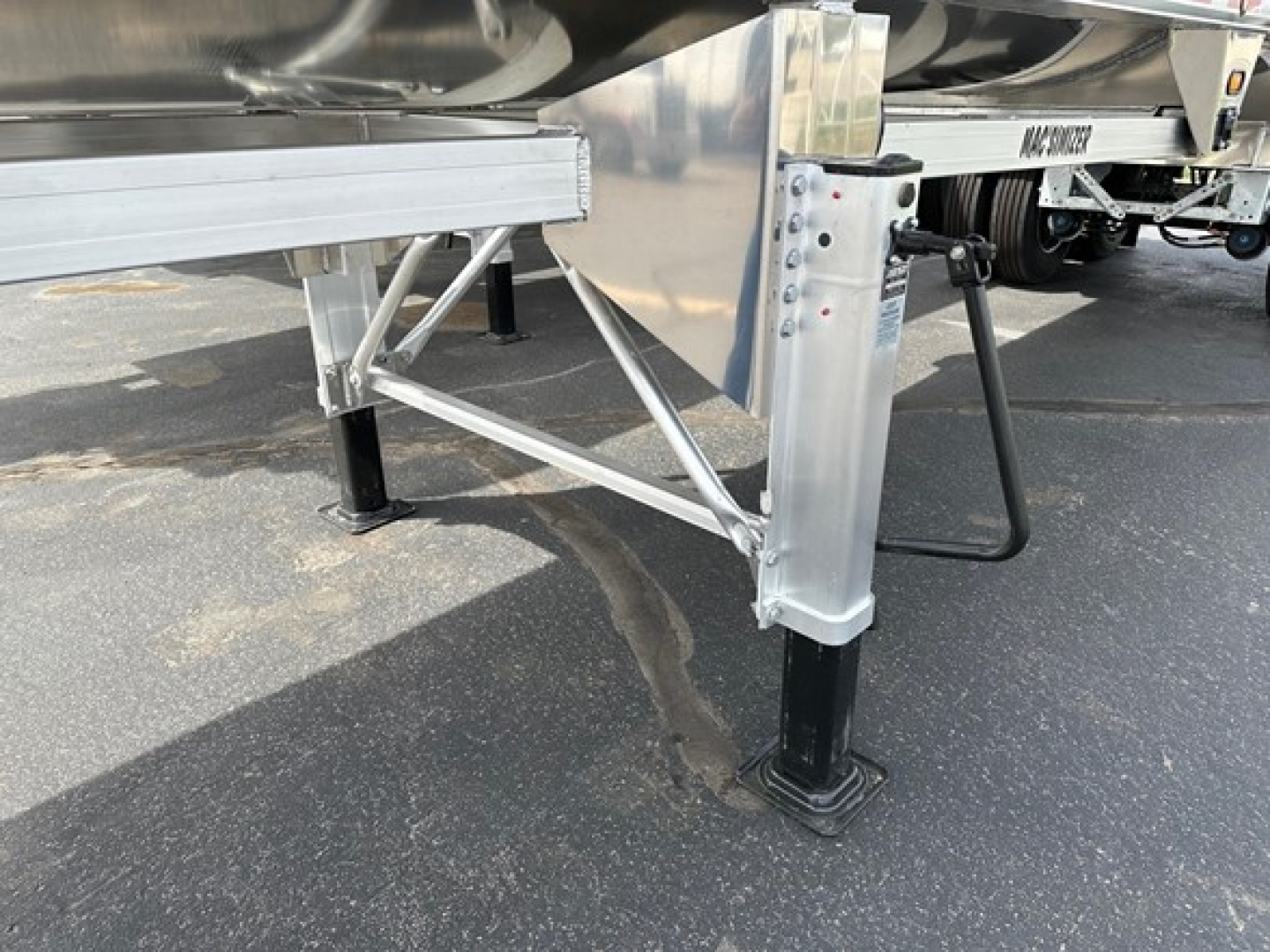 Trailer landing gear with aluminum end dump trailer frame and support legs visible