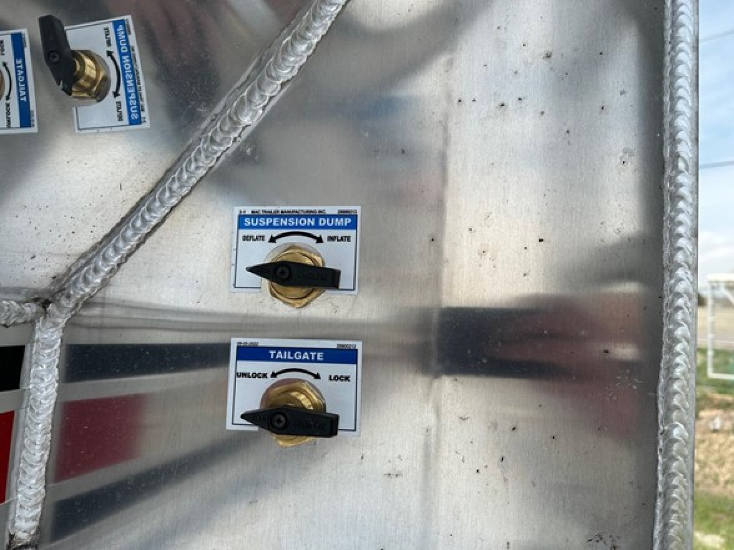 Aluminum end dump trailer control panel showing suspension dump and tailgate rocker switches with labels.