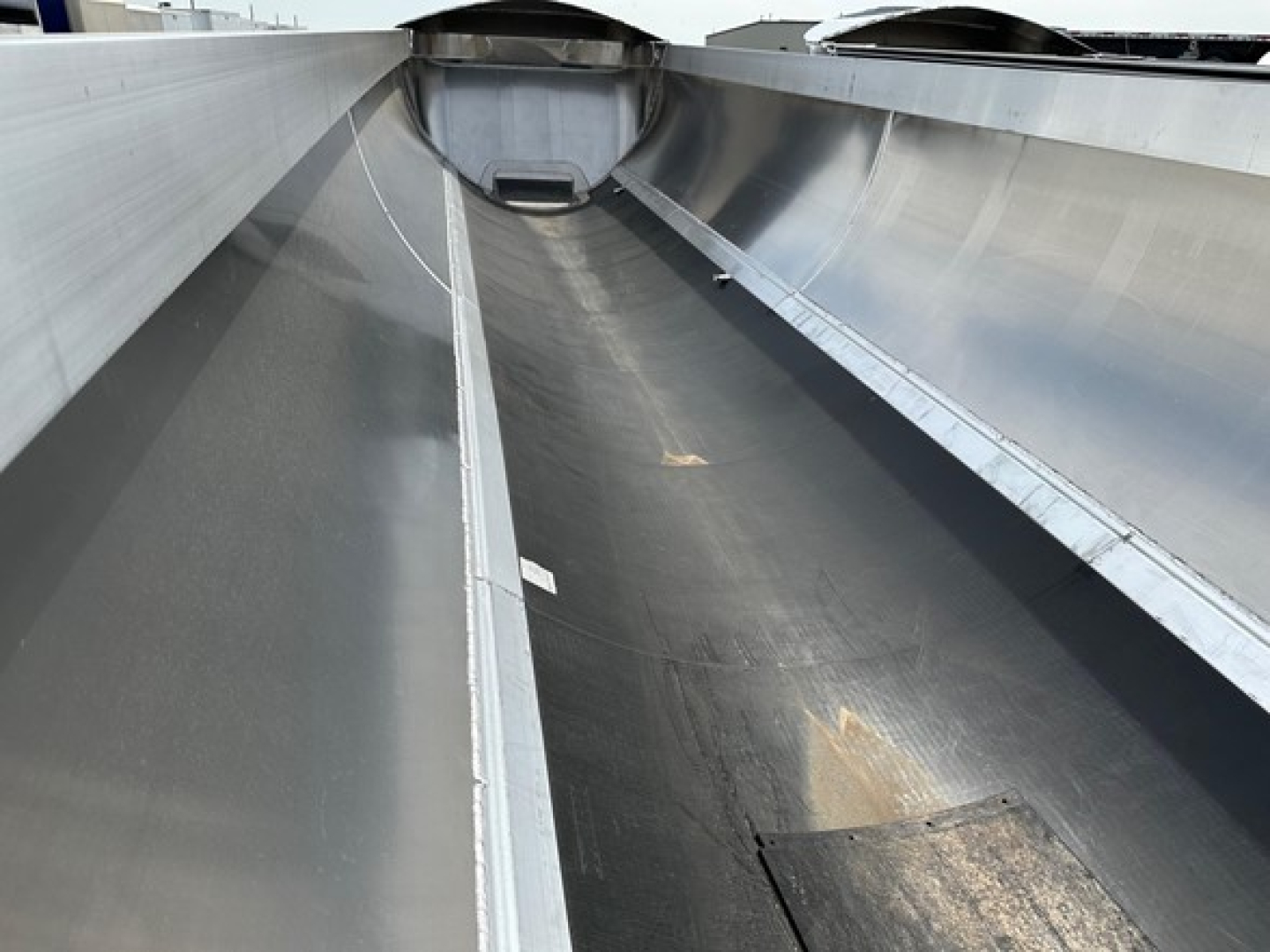Trailer interior showing 1/2 round aluminum end dump with liner; side walls and floor appear smooth metal with some wear; open top and rear area visible.