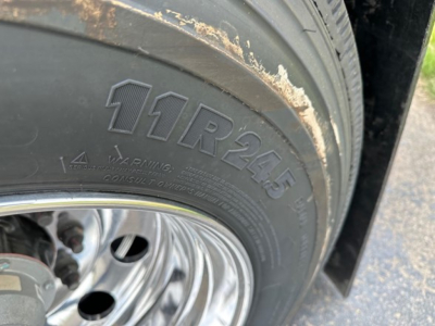 Trailer wheel and tire showing 11R24.5 tire size with polished steel rim on Mac Macsimiser 1/2 Round Alum End Dump.